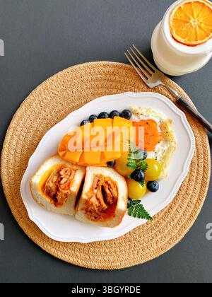 Vassoio per la colazione gourmet con pane ripieno, mango e uova fritte Foto Stock