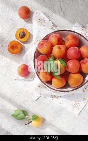 Albicocche fresche in una ciotola, su un tavolo luminoso, luce naturale, vista dall'alto, nessuno Foto Stock