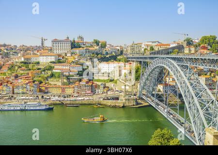 Barche turistiche che navigano sotto il fiume Douro a Porto. Vista aerea del ponte Dom Luis i, del lungomare di Ribeira e delle barche Rabelo da Vila Nova de Gaia, Porto Foto Stock