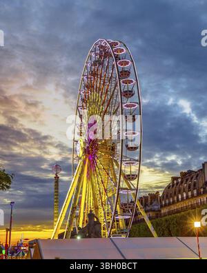 La famosa ruota panoramica icona di Parigi al tramonto vicino all'area del Museo del Louvre con edifici storici sullo sfondo. Scatto verticale Foto Stock
