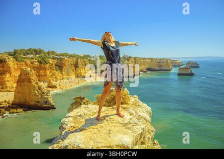 Turismo in Algarve. Libertà lifestyle tourist sul promontorio sopra scenic Praia da Marinha. Caucasica donna spensierata godendo iconico alte scogliere del Mar Foto Stock