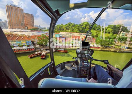 Abitacolo dell'elicottero che vola su Clarke Quay e nell'area Riverside di Singapore. Volo panoramico sopra lo skyline del lungomare con una barca da crociera a Singapor Foto Stock