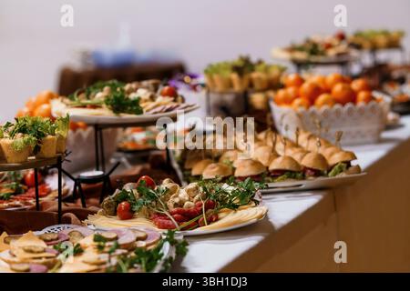 Un ampio buffet con servizio di catering offre deliziosi antipasti, tra cui panini piccoli, frutta colorata, salumi, formaggi e vegetale fresco Foto Stock