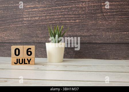 Luglio 6.Calendario di legno con data e orologio da tavolo con campane sul tavolo o ripiano. È estate luglio.alta. Foto Stock