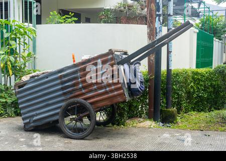 Giacarta, Indonesia - 9 febbraio 2025: Carrello arrugginito con molta spazzatura. Il carrello è parcheggiato in un cortile Foto Stock