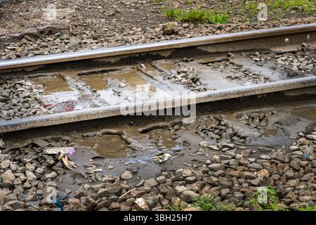 Il binario del treno è coperto di fango e detriti. I binari del treno sono bagnati e fangosi, e ci sono rocce sparse intorno alla zona. La scena è di negligenza A. Foto Stock
