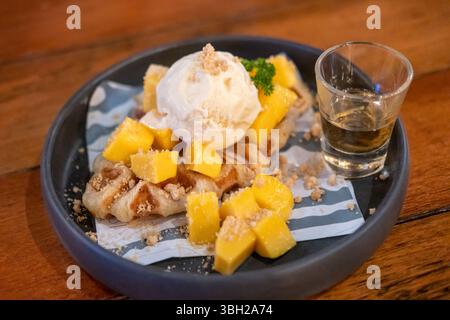 Crostini, ibrido di croissant e waffle al mango, gelato e miele serviti sul piatto Foto Stock