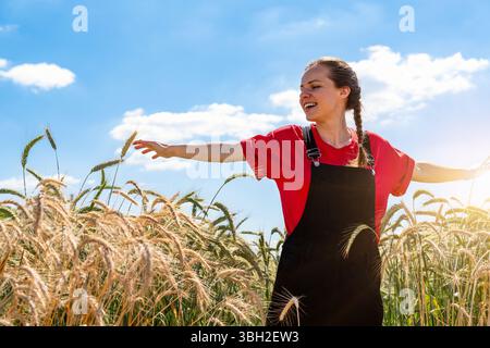 Giovane donna allegra con le braccia allungate sul campo di cereali. Foto Stock