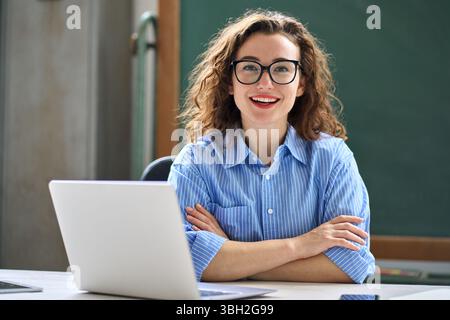 Giovane insegnante online donna felice seduto alla scrivania con computer portatile. Verticale Foto Stock