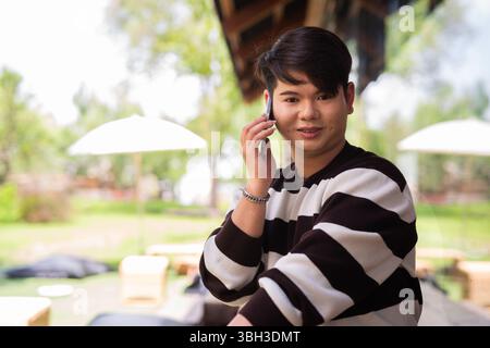 Giovane e carino uomo gay seduto all'aperto nel bar ristorante durante il giorno Foto Stock