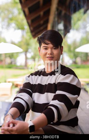 Giovane e carino uomo gay seduto all'aperto nel bar ristorante durante il giorno Foto Stock