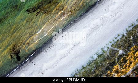 Ripresa aerea di una spiaggia sabbiosa che scorre diagonalmente attraverso l'immagine (acqua a sinistra) Foto Stock