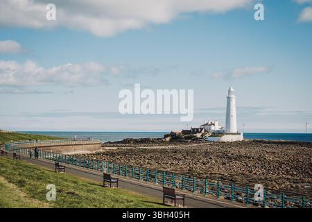 Whitley Bay Regno Unito: 13 aprile 2025: Faro di St Mary che mostra una struttura iconica contro le tranquille acque di Whitley Bay in una giornata di sole limpido Foto Stock