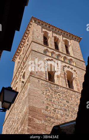 Il campanile in stile mudejar della chiesa di Santo Tomé si erge alto contro un cielo azzurro limpido, caratterizzato da intricati mattoni e motivi geometrici tipici Foto Stock