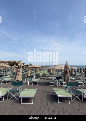 Ombrelloni e lettini chiusi sulla spiaggia mattutina Foto Stock