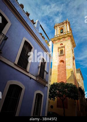 Il campanile di San Bartolomeo sorge sopra edifici colorati nello storico quartiere ebraico di Siviglia, evidenziando una splendida architettura. Foto Stock