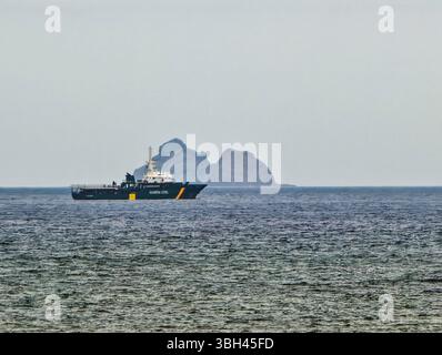 Una motovedetta Guardia Civil opera lungo la costa settentrionale di Lanzarote, supervisionando le acque con l'isola di Alegranza in lontananza. Foto Stock