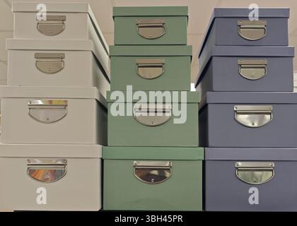 Le scatole di conservazione colorate in bianco, verde e blu sono impilate in modo ordinato sugli scaffali. I manici in metallo aggiungono un tocco elegante e funzionale alla sala operatoria Foto Stock