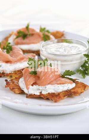 Frittelle croccanti di patate (una frittella, in particolare una di patate grattugiate) con salsa di formaggio cremoso con erbe e salmone Foto Stock