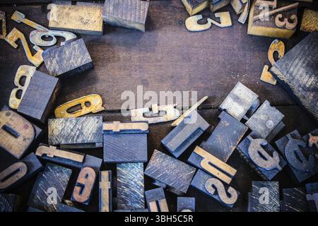 Un mucchio di lettere e numeri vintage in legno e metallo su un vassoio di legno sporco Spazio per una copia Foto Stock