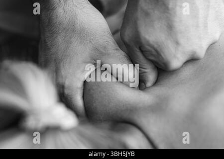 Il fisioterapista esegue un massaggio tissutale profondo sulla spalla del paziente per alleviare la tensione muscolare e migliorare la mobilità in un ambiente terapeutico. Foto Stock