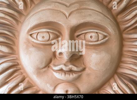 Sorridente faccia del sole in terracotta. Primo piano Foto Stock