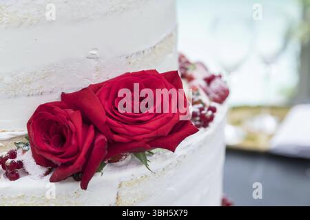 Torta nuziale con due bellissime rose rosse. Ricevimento nuziale. Primo piano Foto Stock
