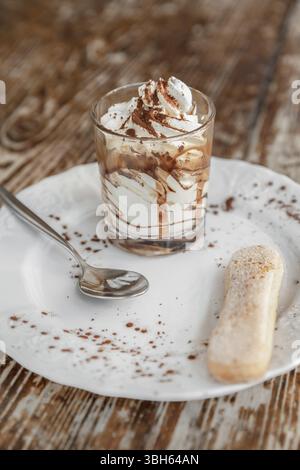 Tradizionale dessert italiano tiramisù in un bicchiere su tavolo rustico scuro Foto Stock