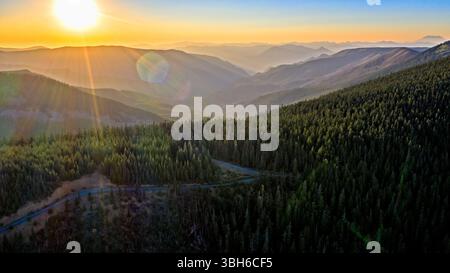 Wahtum Lake, Oregon - 14 agosto 2020: Una vista panoramica del tramonto sulle montagne e sulla foresta, con una strada che si snoda tra gli alberi. Foto Stock