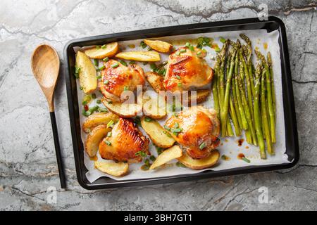 Spalmare il pollo in padella con asparagi e patate da vicino su un tavolo. Vista dall'alto orizzontale Foto Stock
