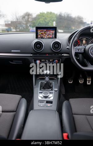Questa immagine mostra il moderno cruscotto di un veicolo Audi, con display digitali, materiali di alta qualità, illuminazione ambientale e comandi intuitivi p Foto Stock