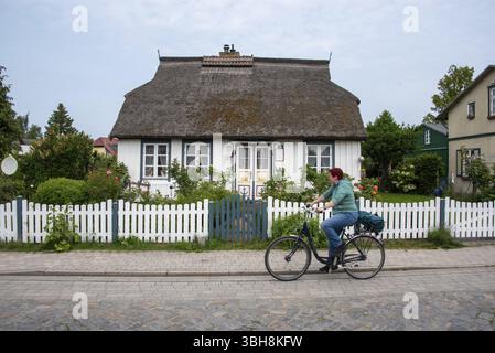 Donna con bicicletta davanti a una casa tradizionale con tetto di paglia, Wieck, Meclemburgo-Vorpommern, Germania, Europa Foto Stock
