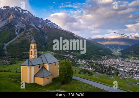 Vista di un tramonto primaverile sulla città di Bormio dalla chiesa della Madonna di Oga. Bormio, distretto di Sondrio, Valtellina, Lombardia, Italia, Europa. Foto Stock