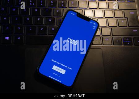 App NHS su un iphone seduto su un computer portatile Foto Stock