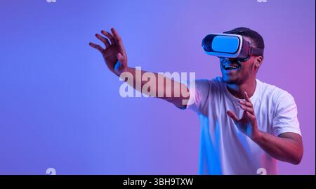 Esperienza virtuale. Eccitato African Man indossare visore VR, giocando videogioco Foto Stock