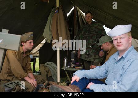 All'interno di una tenda in stile militare, vengono raccolti quattro uomini in abiti adatti al periodo. Sono visibili indumenti, attrezzature per cucire e altri oggetti. Il set Foto Stock