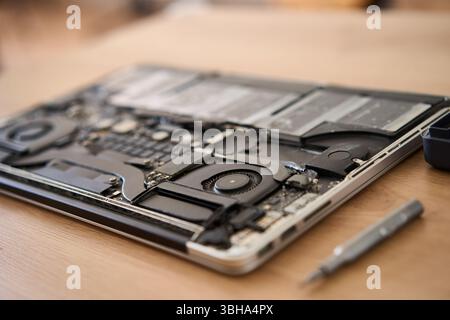 Computer portatile smontato insieme a vari utensili posizionati ordinatamente su una superficie in legno per le riparazioni Foto Stock