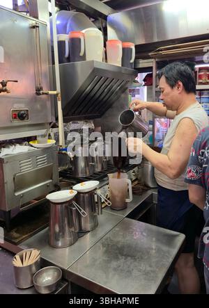 Preparare il tè al latte in stile HK al LAN Fong Yuen è una famosa casa di tè al latte in stile Hong Kong in Gage Street a Hong Kong. Foto Stock