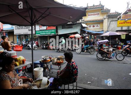 Ho chi Minh City, Vietnam - 12 dicembre 2022: I venditori di Street food aspettano i clienti in una strada di Saigon. Foto Stock