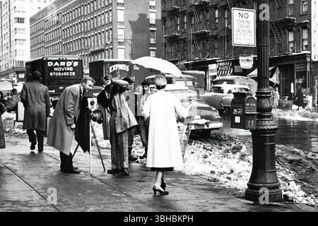 Due uomini che fotografano una donna in un angolo di New York City, gennaio 1958. Foto Stock