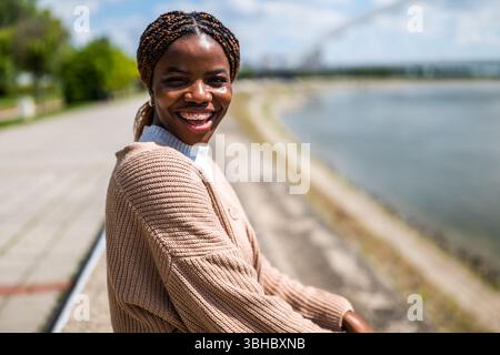 Ritratto di una giovane donna nera allegra che si gode una giornata di sole in città. Foto Stock
