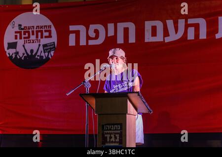 Haifa, Israele - 7 giugno 2025: L'attivista Eliah Levin parla alla folla, parte di una manifestazione di protesta che chiede la fine della guerra, il completamento Foto Stock