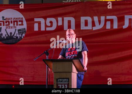 Haifa, Israele - 7 giugno 2025: Il Prof. Amos Guiora parla alla folla, parte di una manifestazione di protesta che chiede la fine della guerra, il completamento dell'accordo con gli ostaggi Foto Stock