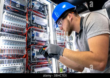 Elettricista nella sala del quadro elettrico. Installazione dei cavi. Cablaggio. Foto Stock
