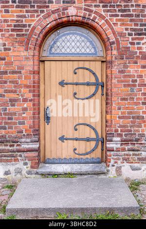 Porte in legno della chiesa. Antico ferro battuto. Arco in mattoni. Foto Stock