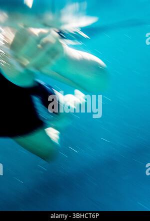 Un'immagine subacquea sfocata di una persona che nuota in una piscina. Foto Stock