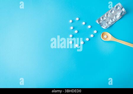 Compresse bianche disposte a forma di cuore con cucchiaio e blister. Rappresentazione simbolica dell'amore e della guarigione nella sanità moderna Foto Stock