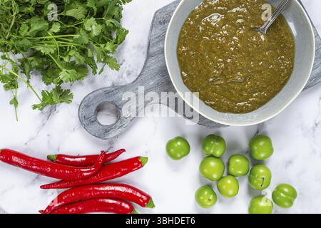 Salsa Tkemali, a base di prugne ciliegine verdi, con ingredienti sul tavolo, vista dall'alto, cucina georgiana, non c'è gente Foto Stock