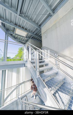 Una donna su una moderna scala in metallo con interni inondati di luce, prolunga Zob con costruzione di ponti per la nuova ferrovia Herman Hesse, Calw, Black Foto Stock
