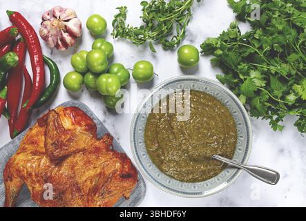 Salsa Tkemali, a base di prugne ciliegine verdi, con ingredienti sul tavolo, pollo al tabacco, vista dall'alto, cucina georgiana, nessuno Foto Stock